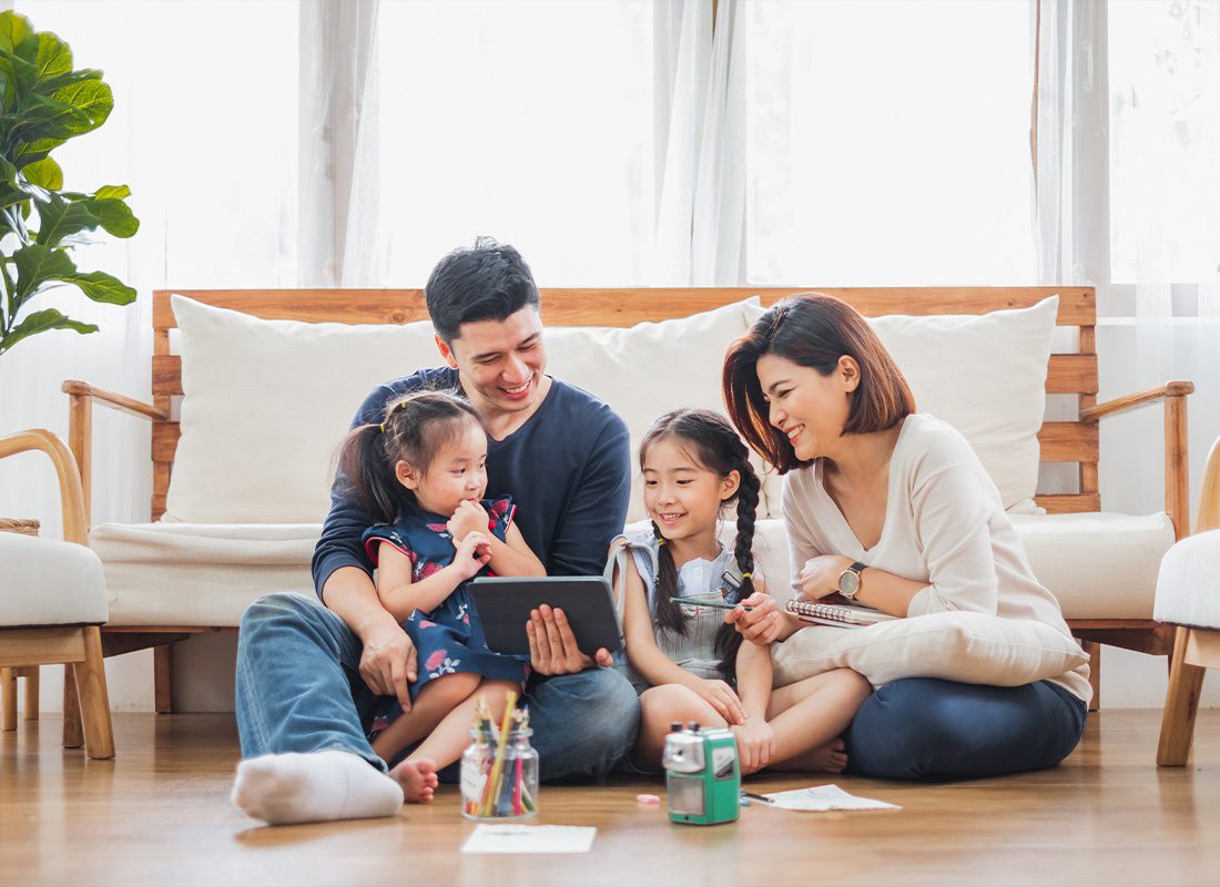 Insurance Solutions - Happy Family Relaxing at Home While Using a Tablet